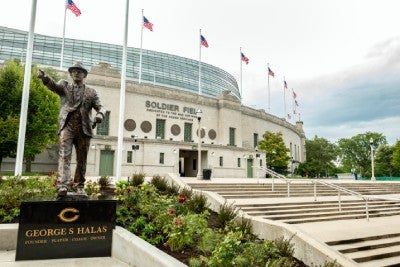 Bronze statue of George Halas made to mimic him calling plays from the sideline, and includes his signature fedora, suit and tie look.