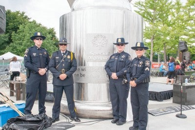 Four uniformed police officers standing in front of the Flame of Hope