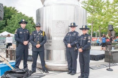 Four uniformed police officers standing in front of the Flame of Hope