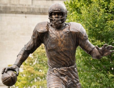 bronze statue of Walter Payton showing him in a running back stance, complete with his uniform and a football in his hand.